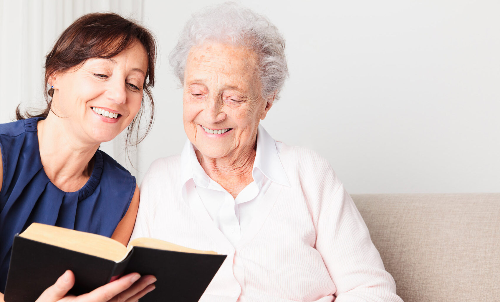 Photo of a woman reading a book with an elderly woman