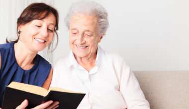 Photo of a woman reading a book with an elderly woman