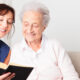 Photo of a woman reading a book with an elderly woman