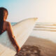 Image of a teen staring at the ocean holding a surfboard