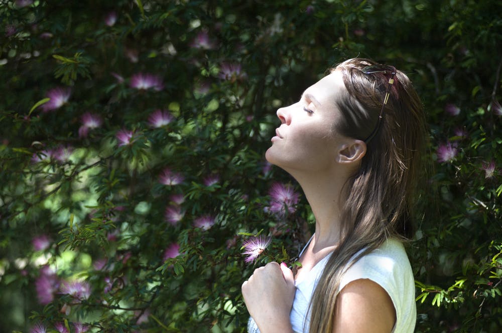 Woman outside smelling flowers